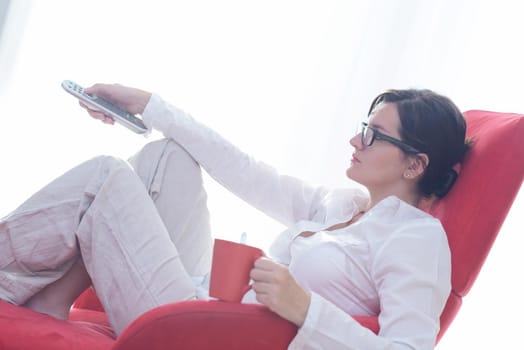 happy young woman relax at home on sofa in bright living room and watching tv