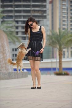 beautiful happy young  woman in black dress with cute small dog puppy have fun on street