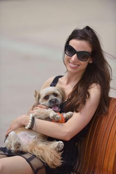 beautiful happy young  woman in black dress with cute small dog puppy have fun on street