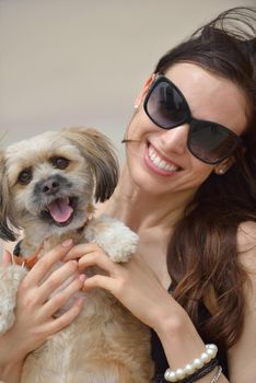 beautiful happy young  woman in black dress with cute small dog puppy have fun on street