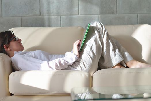 Young woman at home relaxing in her lliving room reading a digital tablet PC surf internet and work