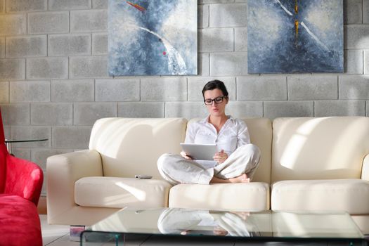 Young woman at home relaxing in her lliving room reading a digital tablet PC surf internet and work