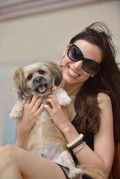 beautiful happy young  woman in black dress with cute small dog puppy have fun on street