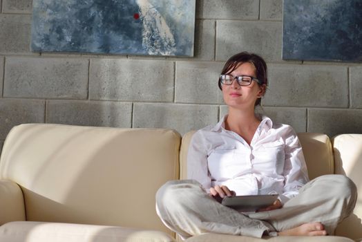 Young woman at home relaxing in her lliving room reading a digital tablet PC surf internet and work