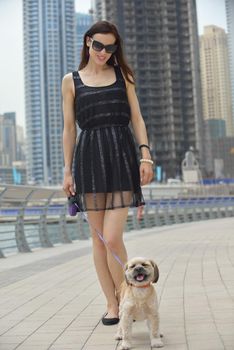 beautiful happy young  woman in black dress with cute small dog puppy have fun on street