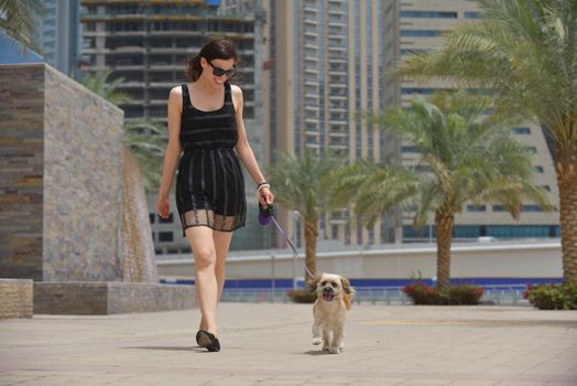 beautiful happy young  woman in black dress with cute small dog puppy have fun on street