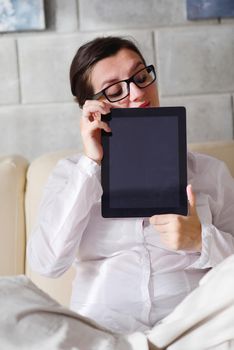 Young woman at home relaxing in her lliving room reading a digital tablet PC surf internet and work