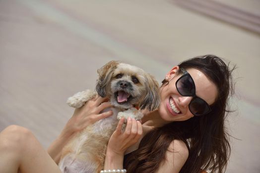 beautiful happy young  woman in black dress with cute small dog puppy have fun on street