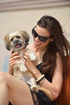 beautiful happy young  woman in black dress with cute small dog puppy have fun on street