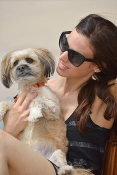 beautiful happy young  woman in black dress with cute small dog puppy have fun on street