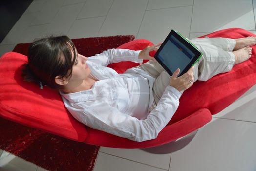 Young woman at home relaxing in her lliving room reading a digital tablet PC surf internet and work