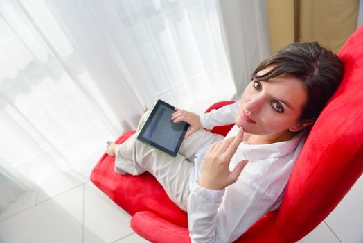 Young woman at home relaxing in her lliving room reading a digital tablet PC surf internet and work