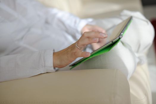 Young woman at home relaxing in her lliving room reading a digital tablet PC surf internet and work