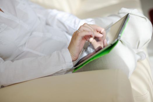 Young woman at home relaxing in her lliving room reading a digital tablet PC surf internet and work