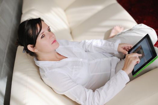 Young woman at home relaxing in her lliving room reading a digital tablet PC surf internet and work