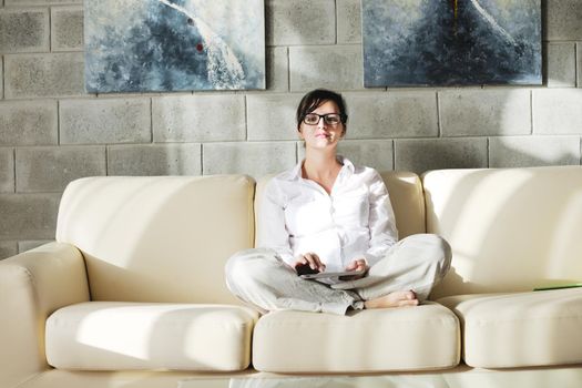 Young woman at home relaxing in her lliving room reading a digital tablet PC surf internet and work