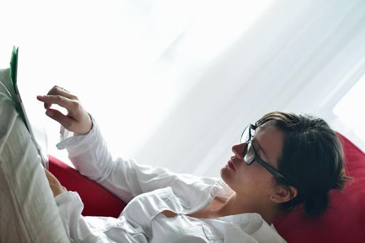 Young woman at home relaxing in her lliving room reading a digital tablet PC surf internet and work