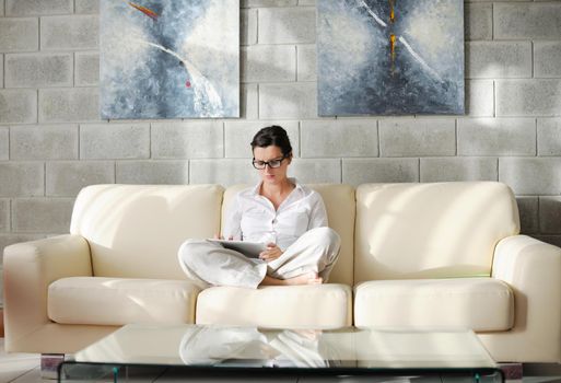 Young woman at home relaxing in her lliving room reading a digital tablet PC surf internet and work