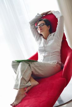 Young woman at home relaxing in her lliving room reading a digital tablet PC surf internet and work