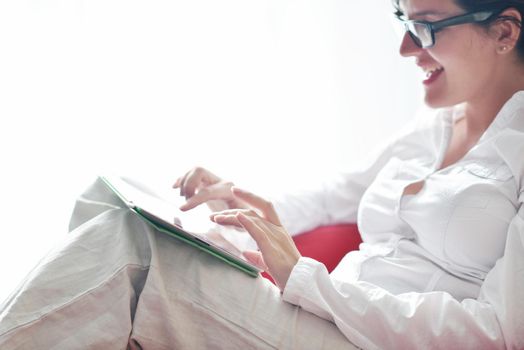 Young woman at home relaxing in her lliving room reading a digital tablet PC surf internet and work