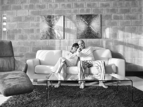 Relaxed young  couple watching tv at home in bright living room