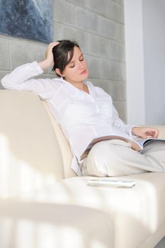 happpy young woman reading magazina at home in comfortabel sofa and bright living room