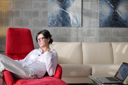 happy young woman relax at home on sofa in bright living room and watching tv