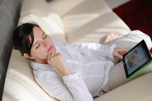 Young woman at home relaxing in her lliving room reading a digital tablet PC surf internet and work