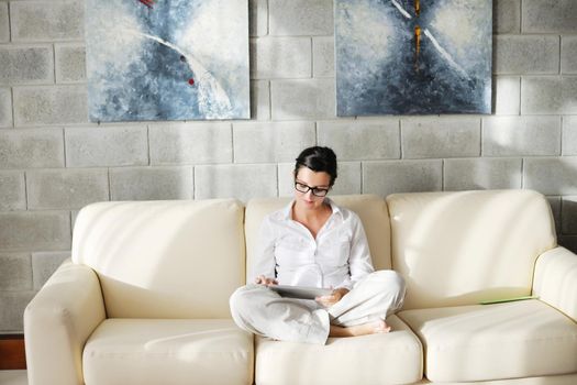 Young woman at home relaxing in her lliving room reading a digital tablet PC surf internet and work