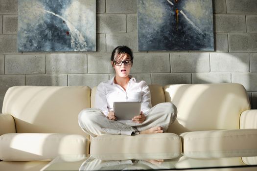 Young woman at home relaxing in her lliving room reading a digital tablet PC surf internet and work