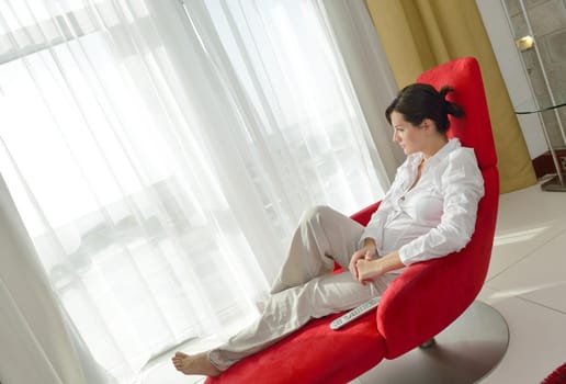 happy young woman relax at home on sofa in bright living room and watching tv