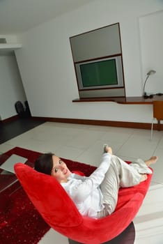 happy young woman relax at home on sofa in bright living room and watching tv