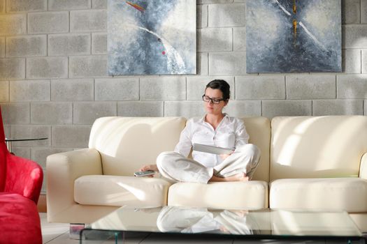 Young woman at home relaxing in her lliving room reading a digital tablet PC surf internet and work