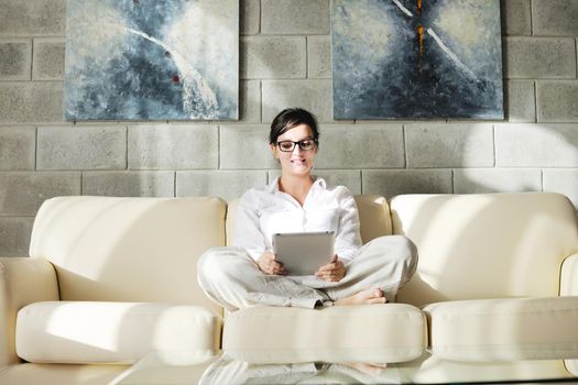 Young woman at home relaxing in her lliving room reading a digital tablet PC surf internet and work