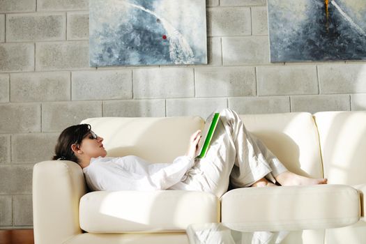 Young woman at home relaxing in her lliving room reading a digital tablet PC surf internet and work