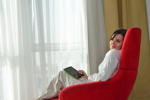 Young woman at home relaxing in her lliving room reading a digital tablet PC surf internet and work