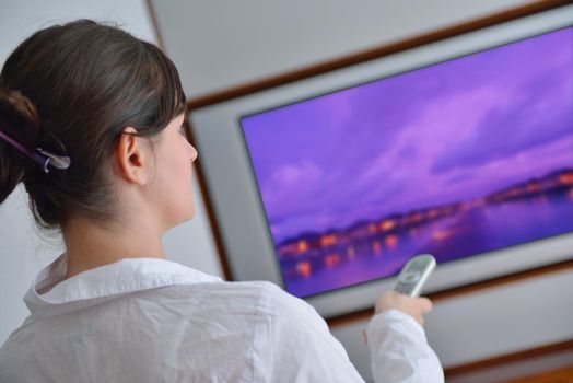 happy young woman watching tv at modern home livingroom