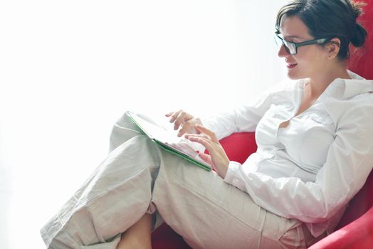 Young woman at home relaxing in her lliving room reading a digital tablet PC surf internet and work