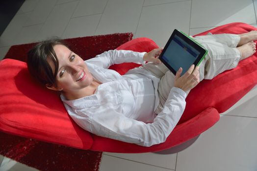 Young woman at home relaxing in her lliving room reading a digital tablet PC surf internet and work