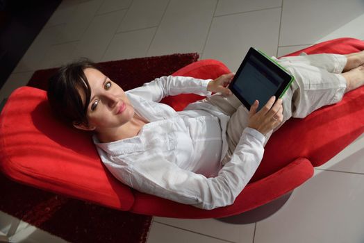 Young woman at home relaxing in her lliving room reading a digital tablet PC surf internet and work