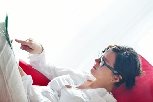 Young woman at home relaxing in her lliving room reading a digital tablet PC surf internet and work