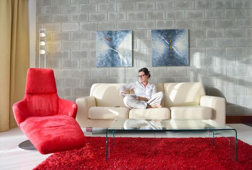 Young woman at home relaxing in her lliving room reading a digital tablet PC surf internet and work