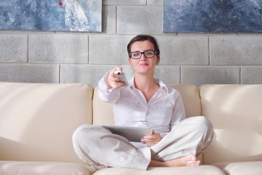 Young woman at home relaxing in her lliving room reading a digital tablet PC surf internet and work