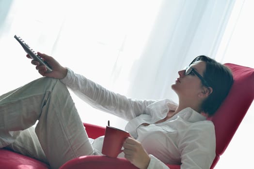 happy young woman relax at home on sofa in bright living room and watching tv