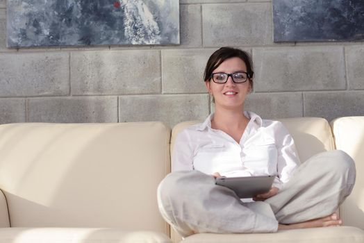 Young woman at home relaxing in her lliving room reading a digital tablet PC surf internet and work