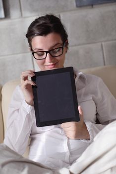 Young woman at home relaxing in her lliving room reading a digital tablet PC surf internet and work