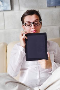 Young woman at home relaxing in her lliving room reading a digital tablet PC surf internet and work