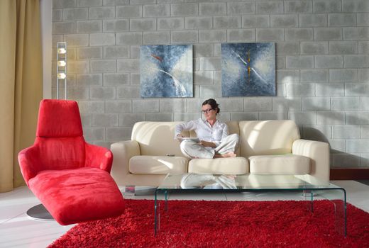 Young woman at home relaxing in her lliving room reading a digital tablet PC surf internet and work