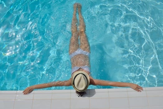 Happy smiling woman with hat and sunglasses  in swimming pool at tropical resort