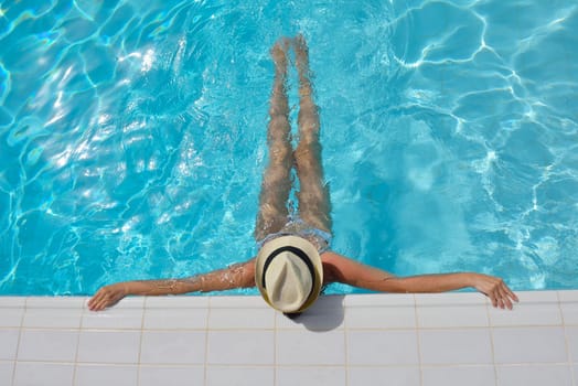 Happy smiling woman with hat and sunglasses  in swimming pool at tropical resort